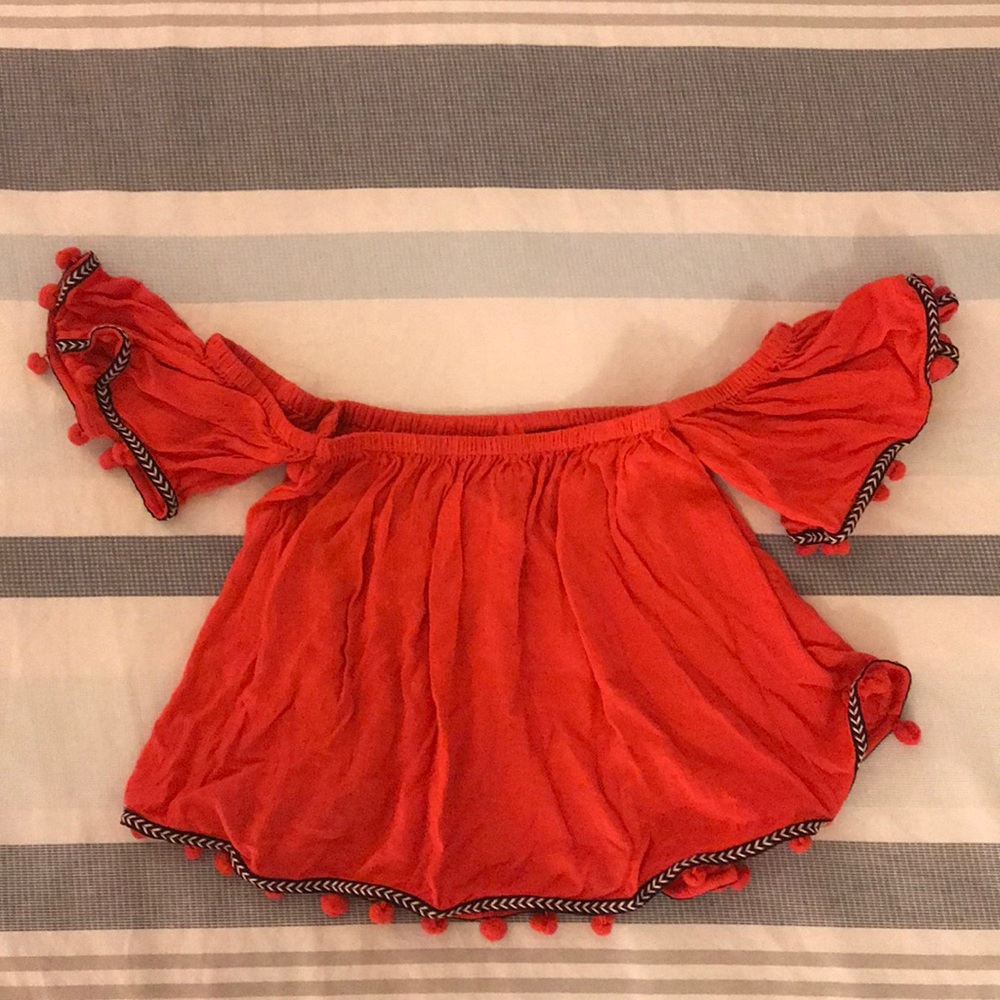Off the shoulder shirt with pompoms.